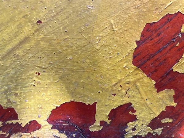 Grunge background texture, yellow peeling paint exposes old cracked varnish on tinted wood. Worn out, aged, damaged vintage lacquered furniture surface with rough, bubbling, chipping coat layers.
