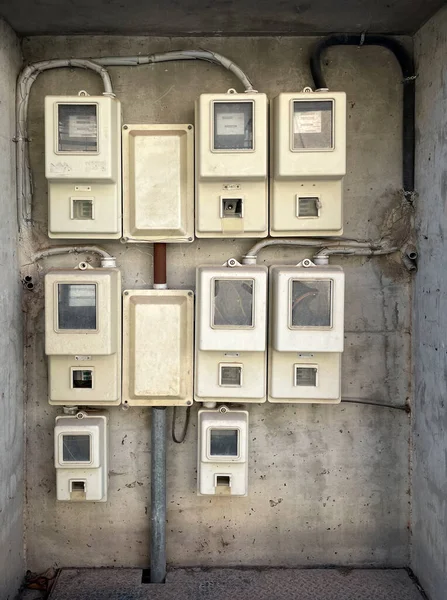 Electricity meters group in the box, power control unit on the wall. Closeup of energy meter attached to the outside wall of a multi-family apartment building. Electrical equipment, residential area.