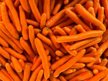 A pile of carrots for sale, close-up as a background. Lots of carrots on the farmer's market stand. Local harvest, organic products at Laiki Agora on the streets of Athens, Greece. clipart