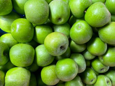Tatlı ama turta aromalı popüler bir mutfak elması, Avustralya 'da 1868 civarında yetişen canlı yeşil Granny Smith elmasıdır. Arkaplan olarak yeşil elma yığını, doku. Sağlıklı beslenme.