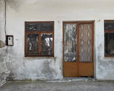 Eski Akdeniz evi dış duvar, yıpranmış gri ahşap panjurlar. Çatlamış cepheli terk edilmiş bir bina, dökülen eski alçı tuğlalar. Atina, Yunanistan.