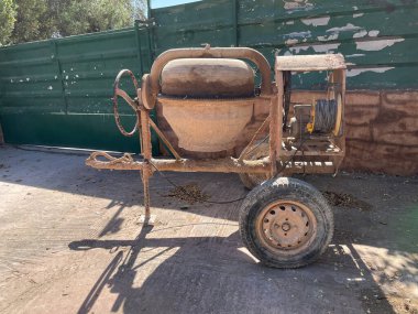 Boş beton karıştırıcı. Şehir caddesi, inşaat alanı bir konut binasının ön cephesinde. İki tekerlekli boş beton karıştırıcı bir inşaatçı. Yenileme, yeniden yapılandırma.