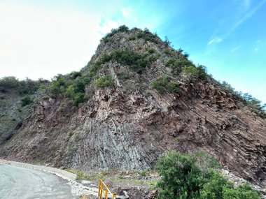 Yeşil yamaçlar ve uzak dağlar, köknar ağaçları ormanlarıyla kaplı, bulutlu, hala sakin, ama yağmur fırtınasından birkaç dakika önce çabucak kararan gökyüzü. Uzak bir dağlık köyden görüntü. Yunanistan.