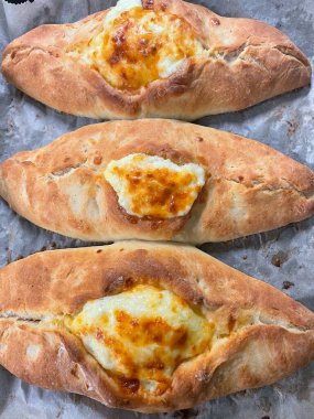 Geleneksel Gürcü pastası. Peynirli ve çiğ yumurtalı Adjarian Khachapuri. Khachapuri siyah arka planda, kırsal tarzda. Malzemeli Adjara Khachapuri. Gürcistan mutfağı