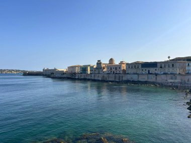 Sahil şeridi boyunca evleri olan bir sahil kasabası. Sakin su, deniz ya da büyük bir koy, sahil boyunca uzanan tarihi binaların pastel renklerini yansıtır. Kilise ya da dini bina. 