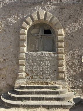 Eski bir binanın ön cephesi. Penceredeki kapalı panjurlar. İtalya, Sicilya 'da güneşli bir sokağa bakan pencere..