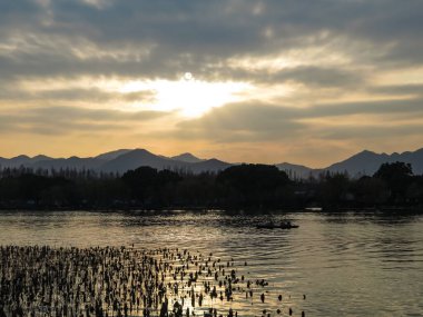 Gün batımında dağları olan sakin bir deniz manzarası. Dramatik gökyüzü ve bulut manzarası. Seyahat, geçmiş ve blog gibi şeyler için. Kavramları. Batı Gölü. Hangzhou şehrinin popüler parkı.