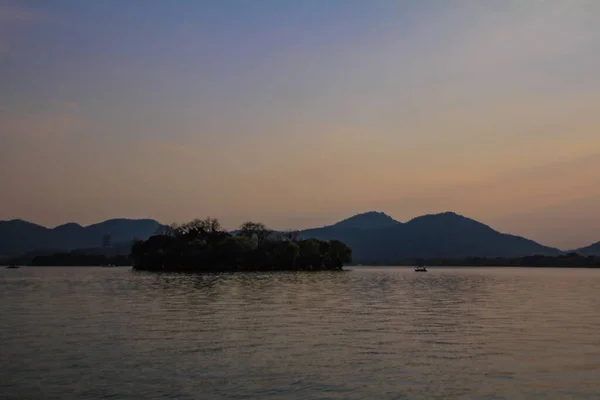 一个轮廓的岛屿和船在平静的海面上航行 夕阳西下的山脉背景 美丽的天空旅行 博客等 西湖杭州人民公园中国 — 图库照片