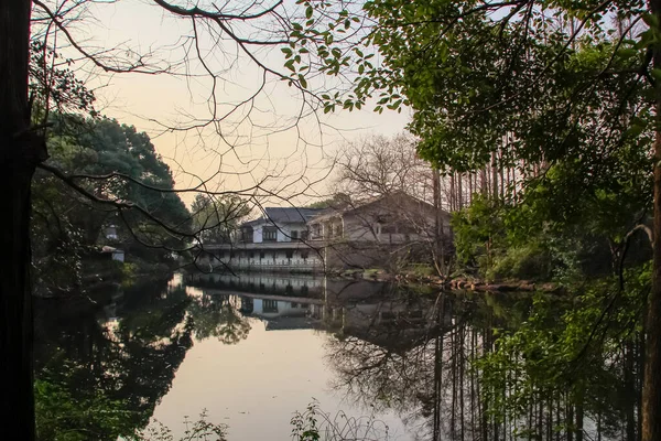 手前の木と日没時の穏やかな海を背景にした中国風の家 水の反射 旅行のために 背景の概念 西湖だ 杭州市の人気公園中国 — ストック写真