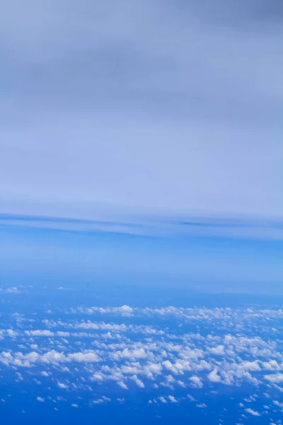 Cloudscape background. View from above, out of an airplane window. Grey cloudy sky.