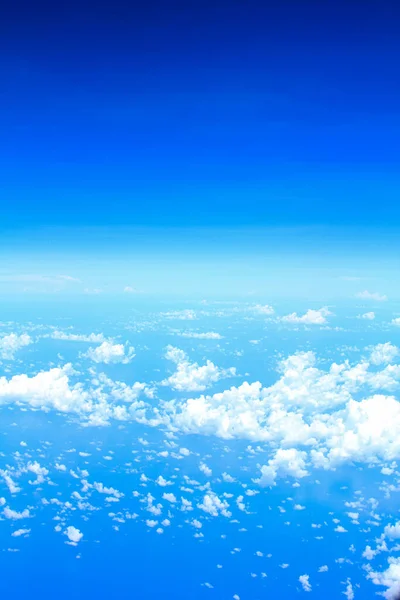 Cloudscape background. View from above, out of an airplane window. White clouds and blue sky with different shades.