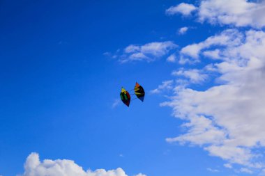 Gökyüzünün alt manzarası. Mavi gökyüzünde beyaz bulutlarla uçan uçurtma.