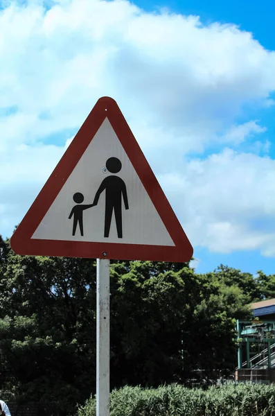 A warning sign of pedestrian on or crossing road ahead. This sign warns motorists and cyclists of the possible presence of pedestrians on adjacent to or crossing the road ahead.