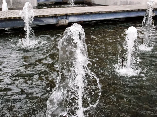 stock image Water fountain springs, water spout of fountain pool in a park. the texture of waterdrops. Transparent frozen visible drops of water in the air. The movement and fragment of a splashing water stream