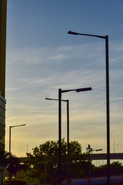 Gün batımında sokak lambasına yakın çekim, arka planda gökyüzü olan şehir ışığı. Şehir manzarası ve şehir merkezi.