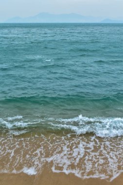 Yumuşak dalgalar, kumsal ve mavi denize yakın çekim. Suyun dokusu, beyaz köpük dalgaları. Deniz manzarası, deniz manzarası, fotokopi alanı olan deniz suyu, yaz tatili konsepti.. 