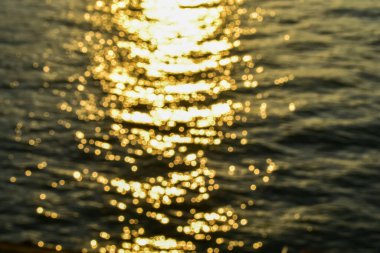 Altın güneş ışığının suya yansımasının Bokeh etkisi. Işıl ışıl güneş ışığıyla gün batımı deniz manzarası. Gün batımı ışığı okyanusa vuruyor. Günbatımı deniz arkaplanı.