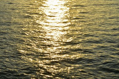 Su üzerindeki altın güneş ışığının yansıması. Işıl ışıl güneş ışığıyla gün batımı deniz manzarası. Gün batımı ışığı okyanusa vuruyor. Günbatımı deniz arkaplanı.