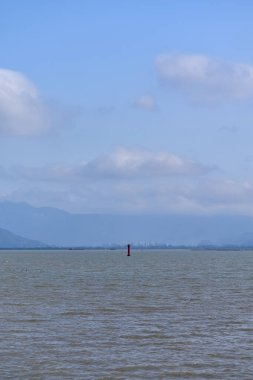 Deniz manzarası ve denizin ortasında kırmızı bir fener manzarası. Güneşli bir günde mavi gökyüzü ile sakin deniz manzarası, doğa kavramı..