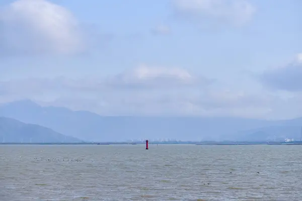 stock image The view of the seascape and a red lighthouse in the center of the sea. Calm seascape with the blue sky in the sunny day, Nature concept.