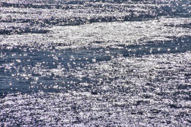 Denize yakın, güneşli bir günde sakin bir su. Parlak dalga deseni, dalga deseni. Deniz arka planı. Doğa konsepti.