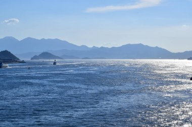 Güneşli bir günde deniz manzarası mavi gökyüzü ve dağ ve arka planda gemiler. Sakin deniz ve su. Deniz arka planı, dalga deseni. Doğa konsepti.