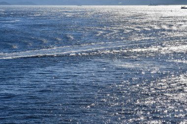 Denize yakın, güneşli bir günde sakin bir su. Parlak dalga deseni, dalga deseni. Deniz arka planı. Doğa konsepti.