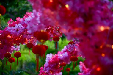 Close-up of the Chinese traditional red lantern decor with artificial peach blossom flower in outdoors. Festive decoration and celebration. Chinese New Year decoration. For background use. clipart