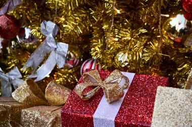 Noel ağaçlarının altındaki renkli süslemelerle hediye kutularının yakın çekimleri. Noel hediyeleri, hediyeler. Şenlik dekorasyonu. Kış mevsimi, kış festivali. Xmas kutlaması. Arkaplan kullanımı için.