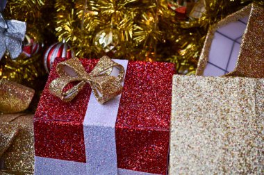 Noel ağaçlarının altındaki renkli süslemelerle hediye kutularının yakın çekimleri. Noel hediyeleri, hediyeler. Şenlik dekorasyonu. Kış mevsimi, kış festivali. Xmas kutlaması. Arkaplan kullanımı için.