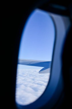 Uçak penceresinden, çarpıcı gökyüzü manzarası ve uçak kanadı olan manzaraya bakıyorum. Seyahat ve ulaşım kavramı.