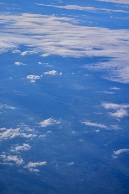 Bulutların altındaki şehir manzaralı uçak penceresinden bakıyorum. Şehrin üzerindeki bulutlar. Havadan bakıyorum. Doğa ve seyahat kavramı.