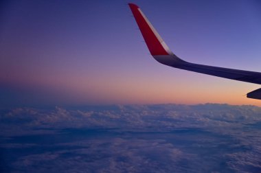 Gün batımı gökyüzü ile uçak penceresinden bakıyorum. Romantik gökyüzü, altın saatler, bulutlu renkli günbatımı gökyüzü. Çarpıcı bulutlar ve gökyüzü. Doğa konsepti. Arkaplan kullanımı için.