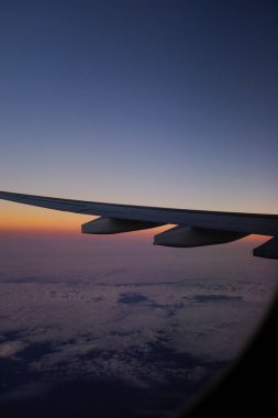 Gün batımı gökyüzü ile uçak penceresinden bakıyorum. Romantik gökyüzü, altın saatler, bulutlu renkli günbatımı gökyüzü. Çarpıcı bulutlar ve gökyüzü. Doğa konsepti. Arkaplan kullanımı için.