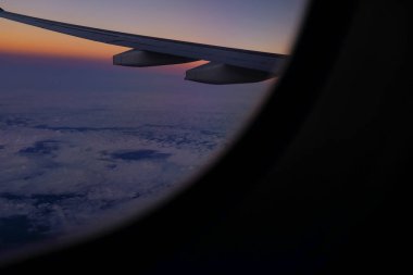 Gün batımı gökyüzü ile uçak penceresinden bakıyorum. Romantik gökyüzü, altın saatler, bulutlu renkli günbatımı gökyüzü. Çarpıcı bulutlar ve gökyüzü. Doğa konsepti. Arkaplan kullanımı için.
