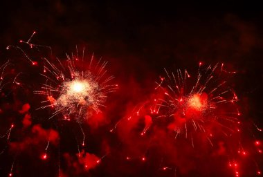 Gece gökyüzünde, patlama sırasında dumanla sergilenen göz kamaştırıcı ve renkli havai fişekler. Gerçek havai fişek arka planı. Siyah arka planda parlayan gerçek havai fişeklerin soyutlanması. Kutlama için.