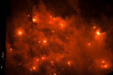 Gece gökyüzünde, patlama sırasında dumanla sergilenen göz kamaştırıcı ve renkli havai fişekler. Gerçek havai fişek arka planı. Siyah arka planda parlayan gerçek havai fişeklerin soyutlanması. Kutlama için.