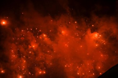 Gece gökyüzünde, patlama sırasında dumanla sergilenen göz kamaştırıcı ve renkli havai fişekler. Gerçek havai fişek arka planı. Siyah arka planda parlayan gerçek havai fişeklerin soyutlanması. Kutlama için.