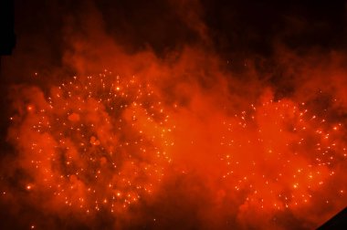 Gece gökyüzünde, patlama sırasında dumanla sergilenen göz kamaştırıcı ve renkli havai fişekler. Gerçek havai fişek arka planı. Siyah arka planda parlayan gerçek havai fişeklerin soyutlanması. Kutlama için.