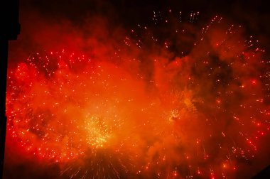 Gece gökyüzünde, patlama sırasında dumanla sergilenen göz kamaştırıcı ve renkli havai fişekler. Gerçek havai fişek arka planı. Siyah arka planda parlayan gerçek havai fişeklerin soyutlanması. Kutlama için.