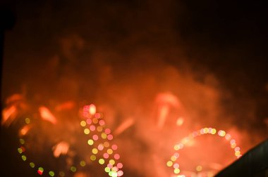 Gece gökyüzünde renkli havai fişeklerin Bokeh etkisi. Gerçek havai fişek arka planı. Siyah arka planda parlayan gerçek havai fişeklerin soyutlanması. Kutlama için parlayan havai fişek gösterisi.