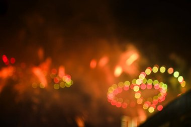 Gece gökyüzünde renkli havai fişeklerin Bokeh etkisi. Gerçek havai fişek arka planı. Siyah arka planda parlayan gerçek havai fişeklerin soyutlanması. Kutlama için parlayan havai fişek gösterisi.