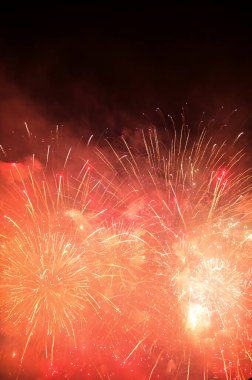 Gece gökyüzünde göz kamaştırıcı ve renkli havai fişek gösterisi. Gerçek havai fişek arka planı. Siyah arka planda parlayan gerçek havai fişeklerin soyutlanması. Kutlama için parlayan havai fişek gösterisi.