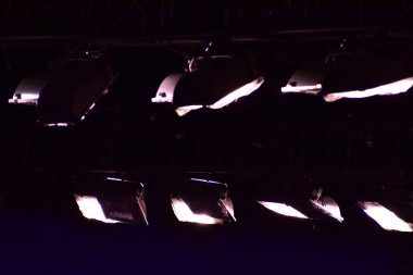 Sahnede tiyatro veya konser salonunun aydınlatılması için profesyonel sahne aydınlatma ekipmanları var. Sahne ışıkları, spot ışıkları ve lazer ışınları. Projektörlerden gelen ışık huzmeleri. Konser ışığı.