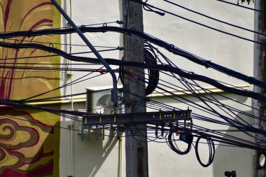 Tayland 'daki direğin dağınık elektrik kablolarına yakın çekim. Elektrik direğine dolanmış kablolar. 