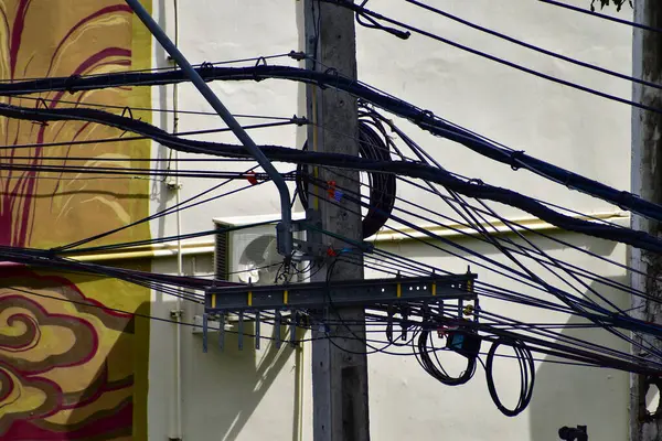 Tayland 'daki direğin dağınık elektrik kablolarına yakın çekim. Elektrik direğine dolanmış kablolar. 