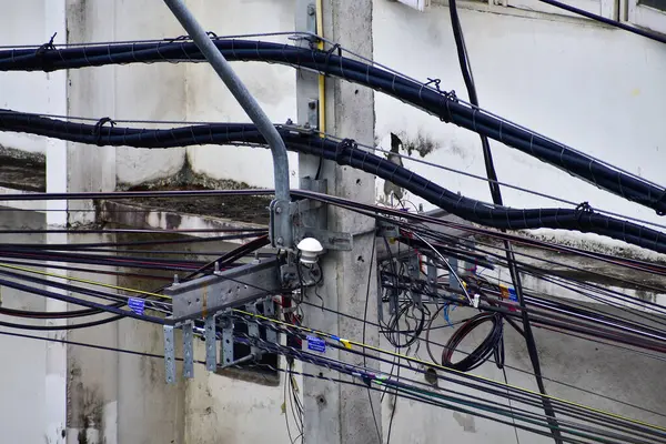Tayland 'daki direğin dağınık elektrik kablolarına yakın çekim. Elektrik direğine dolanmış kablolar. 