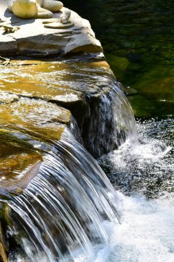 Halka açık bir parktaki şelale manzarası. Su sıçrıyor, su akıyor. Doğa konsepti.