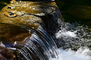 Halka açık bir parktaki şelale manzarası. Su sıçrıyor, su akıyor. Doğa konsepti.