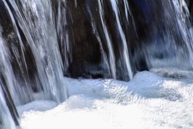 Halka açık bir parktaki şelale manzarası. Su sıçrıyor, su akıyor. Doğa konsepti.